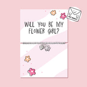 Children’s silver-plated flower girl proposal bracelet with heart and flower charms displayed on a pink “Will You Be My Flower Girl?” card.