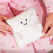 Soft white fluffy envelope pouch with a cute embroidered smiley face, held in someone’s hands while wearing pink cherry-print pyjamas. A cosy gift pouch designed to hold any Letterbox Love bracelet, including boxed bracelets.