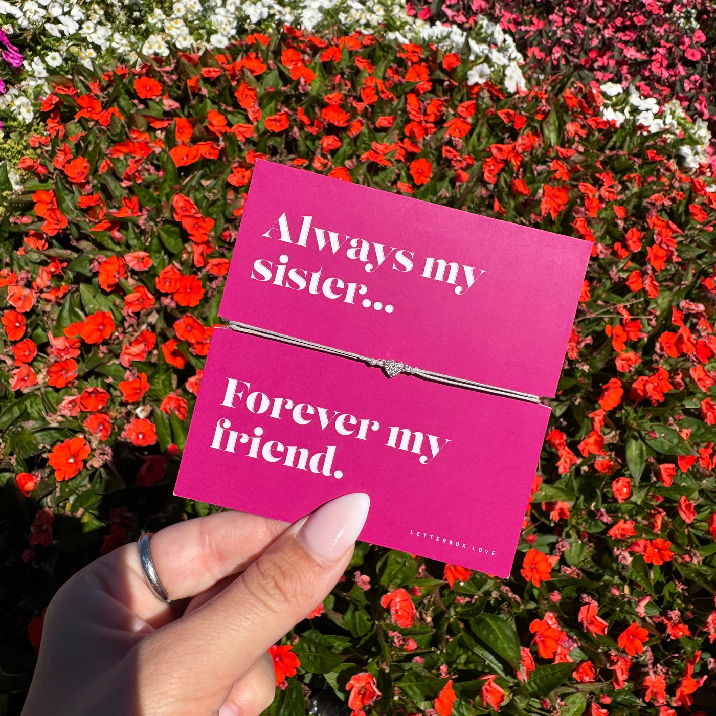 A hand holds a bright pink card with white text reading 'Always my sister.