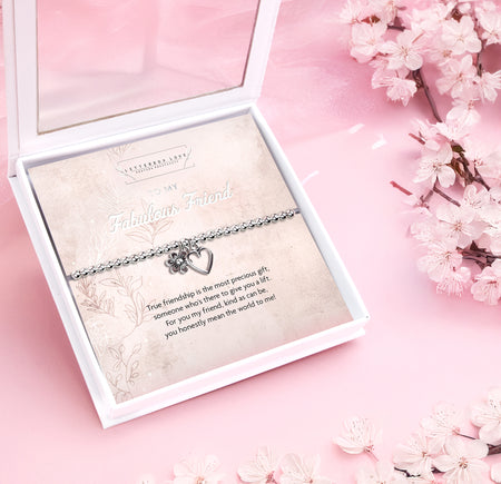 Silver beaded bracelet with heart and flower charms, displayed in a white gift box alongside a card titled 