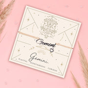 Bracelet with 'Gemini' charm on a branded card with astrological design on a pink background. Zodiac bracelet under £20.