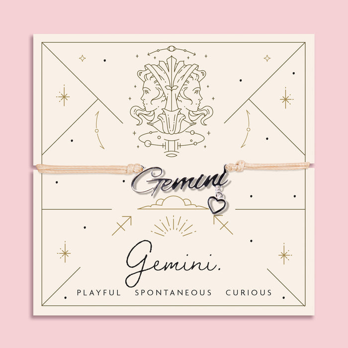 Adjustable peach cord bracelet with a silver 'Gemini' charm and heart pendant, displayed on a zodiac-themed card with a twin illustration and the traits "Playful, Spontaneous, Curious".
