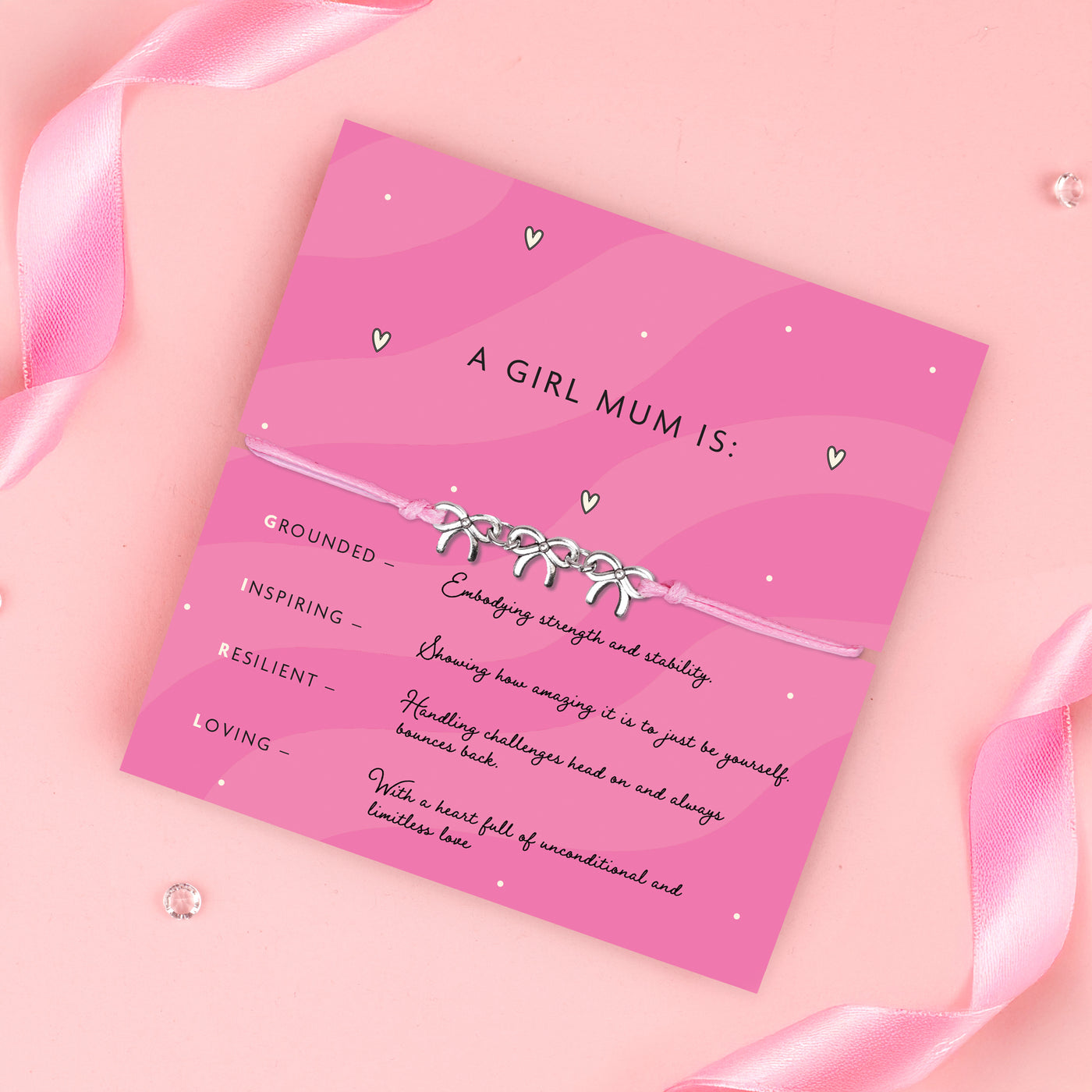 Pink card with text and a bracelet design, surrounded by pink ribbons on a pink background