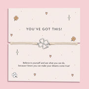 Silver-plated four-leaf clover charm bracelet on a "You’ve Got This!" motivational card with a pink background and daisies. Perfect for inspiring confidence, this charm bracelet makes a thoughtful gift for someone in need of a little encouragement, featuring positive affirmations for women, friends, and those facing challenges.