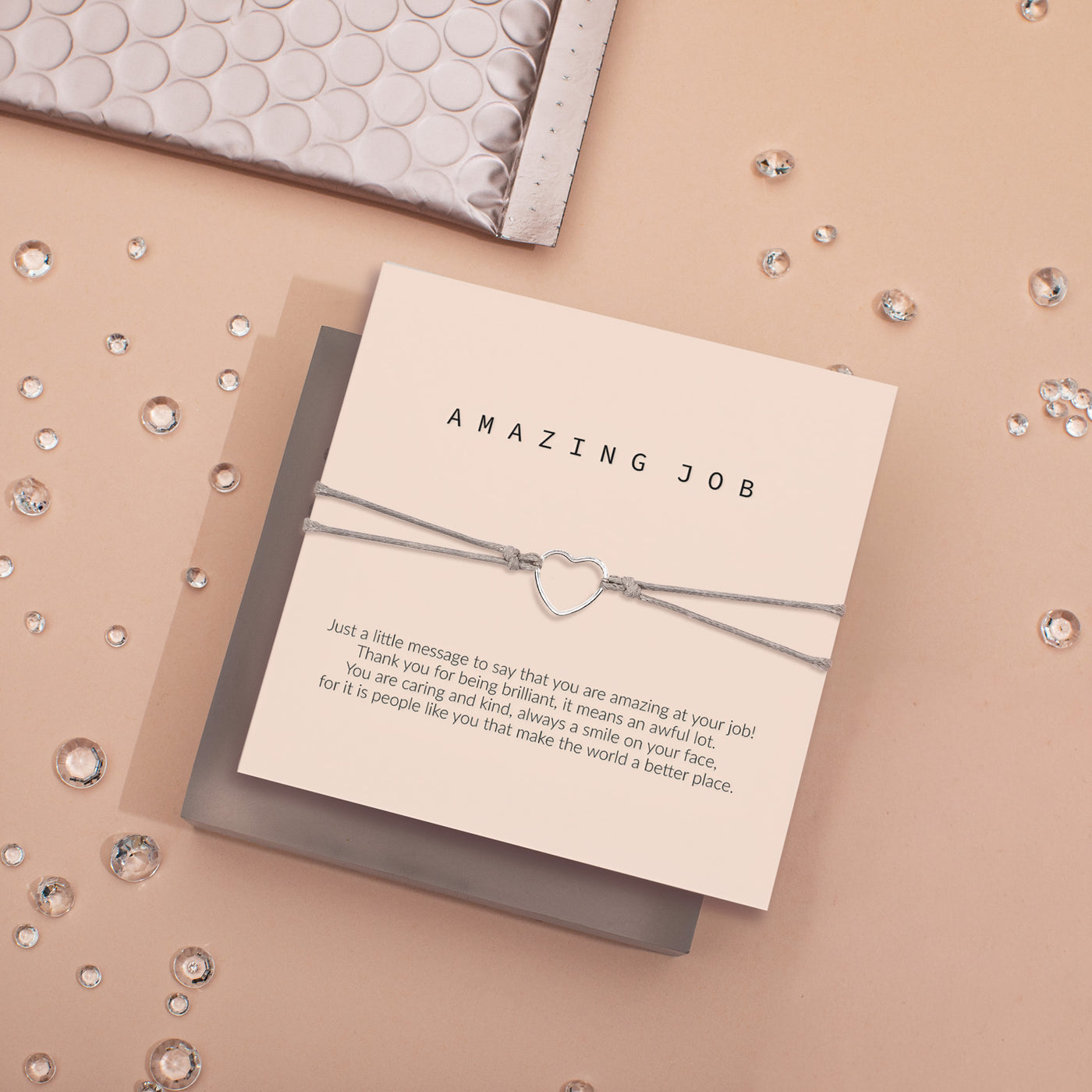 Card with 'Amazing Job' message and heart-shaped charm on a decorative background. Bracelet under £20 for congratulations.