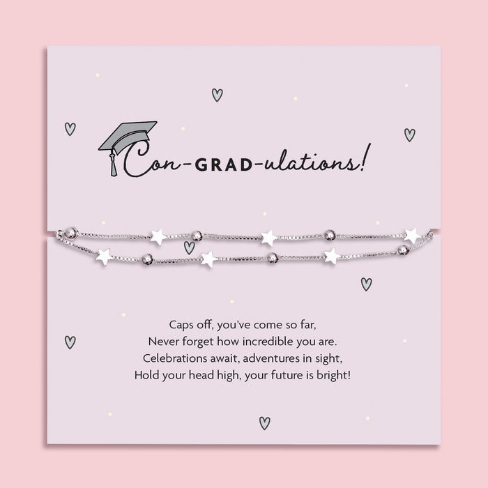 Silver star graduation bracelet on a pale grey card with a mortarboard and poem, titled “Con-GRAD-ulations!” – a perfect gift for her special day.