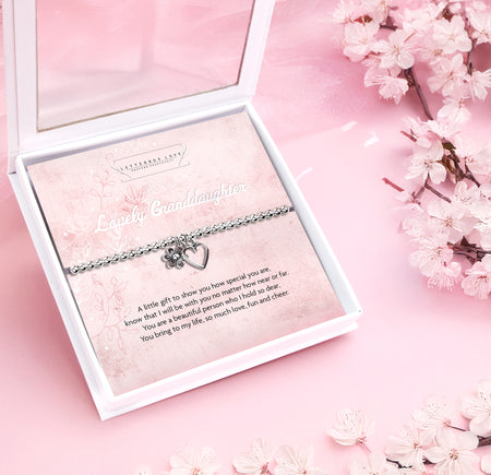 Silver beaded bracelet with heart and flower charms, presented in a white gift box alongside a card titled 