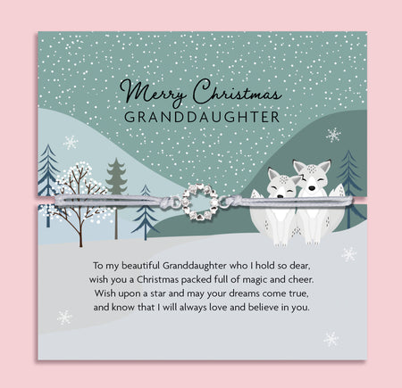 Merry Christmas Granddaughter bracelet featuring a silver wreath charm on an adjustable cord, presented on a festive green card with bells, mistletoe, Christmas trees, and snowy details. Includes a soft white pouch for gifting and safekeeping. A sentimental Christmas jewellery gift for granddaughters of all ages, perfect as a stocking filler, Christmas morning surprise, or heartfelt keepsake from grandparents. A meaningful holiday bracelet celebrating love and family.