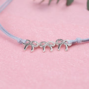Grey cord friendship bracelet with three cute bow bracelets, creating a perfect gift for hen do favours under £10