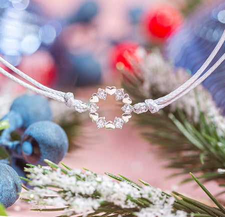 Bracelet with a heart-shaped pendant on a blurred background of berries and foliage