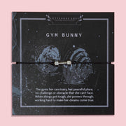 Gym Bunny bracelet featuring a silver-tone dumbbell charm on a black adjustable cord, displayed on a motivational gym-themed card with the message about strength, resilience, and powering through challenges. This fitness bracelet is the perfect gift for gym lovers, workout enthusiasts, personal trainers, and women who love weightlifting or staying active. A unique piece of fitness jewellery and an inspiring keepsake for birthdays, Christmas, or everyday motivation.