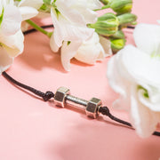 Small dumbbell charm on a friendship bracelet with white flowers around it. A cute gift for a female gym goer