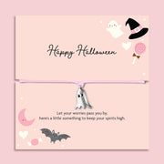 Pink adjustable cord Halloween bracelet with silver plated ghost charm displayed on a pastel pink Happy Halloween sentiment card with spooky ghost, bat, moon and witch hat illustrations.