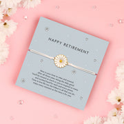 Happy Retirement Daisy Bracelet with a delicate daisy charm on an adjustable white cord, set on a blue card with a heartfelt retirement message.