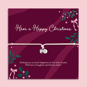 A Christmas-themed poem card featuring a delicate cord bracelet with a silver heart and a pearl charm. The card is deep burgundy with white text reading 'Have a Happy Christmas' and festive green and pink illustrations, set against a light pink background.