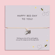Bee-themed birthday bracelet with silver bee and heart charms on an adjustable cord, presented on a “Happy Bee-Day to You” illustrated message card.