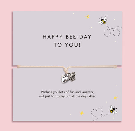 Bee-themed birthday bracelet with silver bee and heart charms on an adjustable cord, presented on a “Happy Bee-Day to You” illustrated message card.