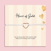 Heart of Gold adjustable white cord bracelet with gold-tone open heart charm displayed on a cream and gold sentiment card reading “Thank you for having a heart of gold.”