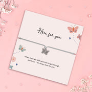 Silver butterfly charm bracelet on a soft grey adjustable cord, presented on a pastel illustrated gift card that reads “Here for you” with a heartfelt message of support, surrounded by delicate butterfly and floral artwork on a pink background.