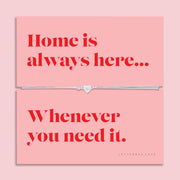 Adjustable grey cord bracelet with a sparkling silver heart charm displayed on a pink sentiment card reading "Home is always here... Whenever you need it", presented in a luxury white butterfly envelope.