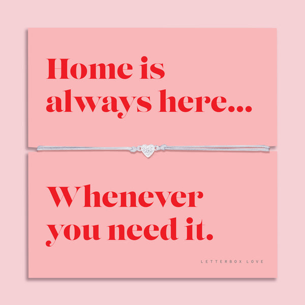 Adjustable grey cord bracelet with a sparkling silver heart charm displayed on a pink sentiment card reading "Home is always here... Whenever you need it", presented in a luxury white butterfly envelope.
