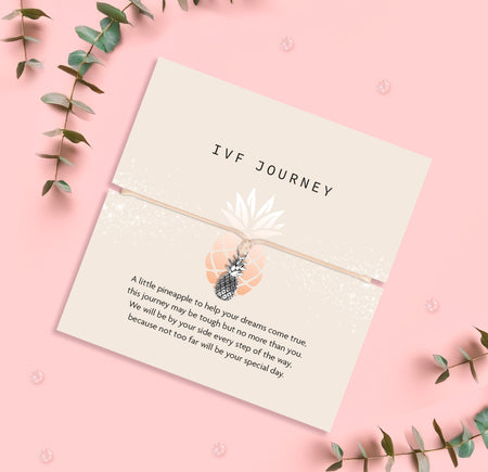 Pineapple charm bracelet for IVF journey, presented with a heartfelt sentiment card offering encouragement and support. The design includes a small silver pineapple charm on a beige cord with a meaningful message.