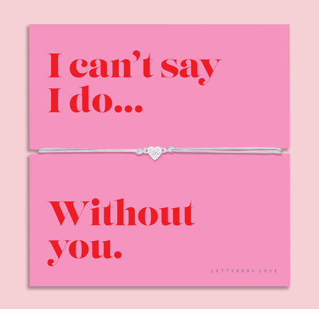 Silver heart charm bracelet on a soft grey adjustable cord, displayed on a vibrant pink sentiment card reading 