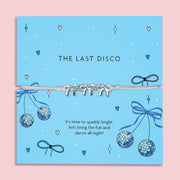 A vibrant blue card with the words "THE LAST DISCO" in black uppercase letters. The card is decorated with fun disco-themed illustrations, including sparkling disco balls, blue bows, hearts, and stars. A delicate bracelet with three silver bow charms on a soft ivory cord is wrapped around the card. Below, the message reads: "It’s time to sparkle bright, let’s bring the fun and dance all night!" The background is plain white, highlighting the bracelet and card design.