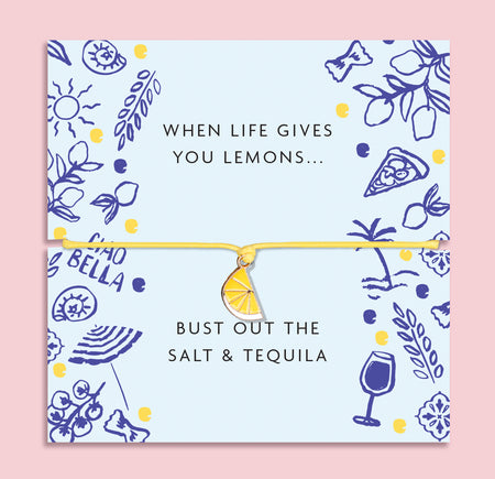 Yellow cord bracelet with an enamel lemon slice charm displayed on a pastel blue card with playful illustrations and the quote 