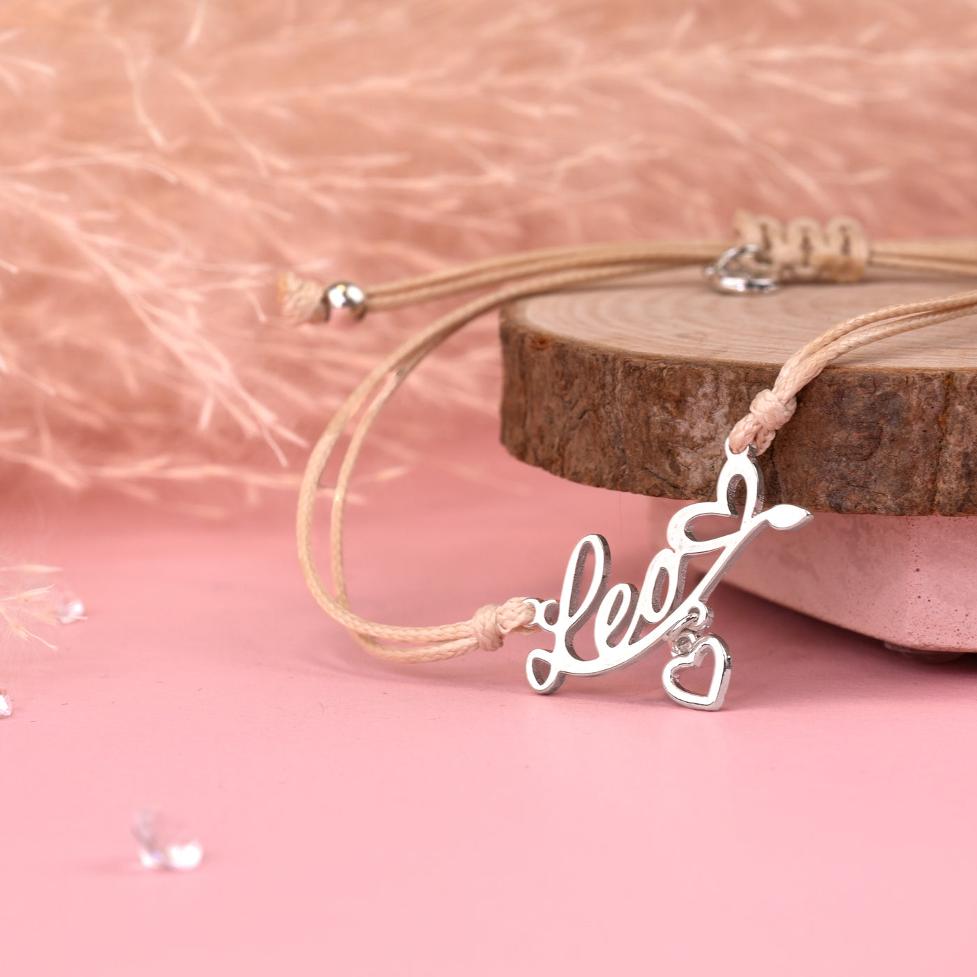 Silver necklace with 'love' pendant on a pink background. Affordable star sign jewellery for women. Leo bracelet under £20