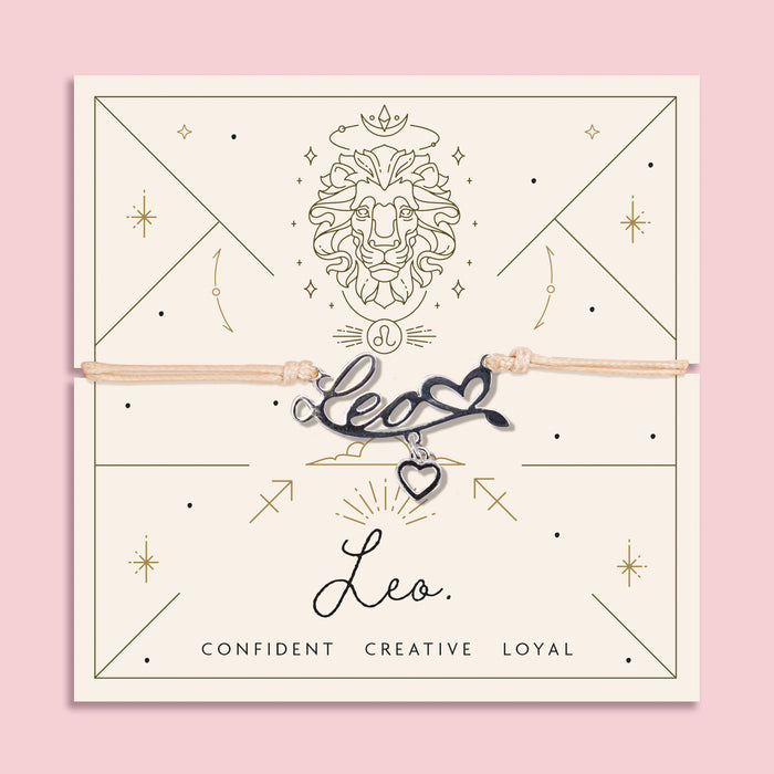 Adjustable beige thread bracelet with a silver 'Leo' charm and heart pendant, displayed on a zodiac-themed backing card featuring a lion illustration and the traits "Confident, Creative, Loyal".