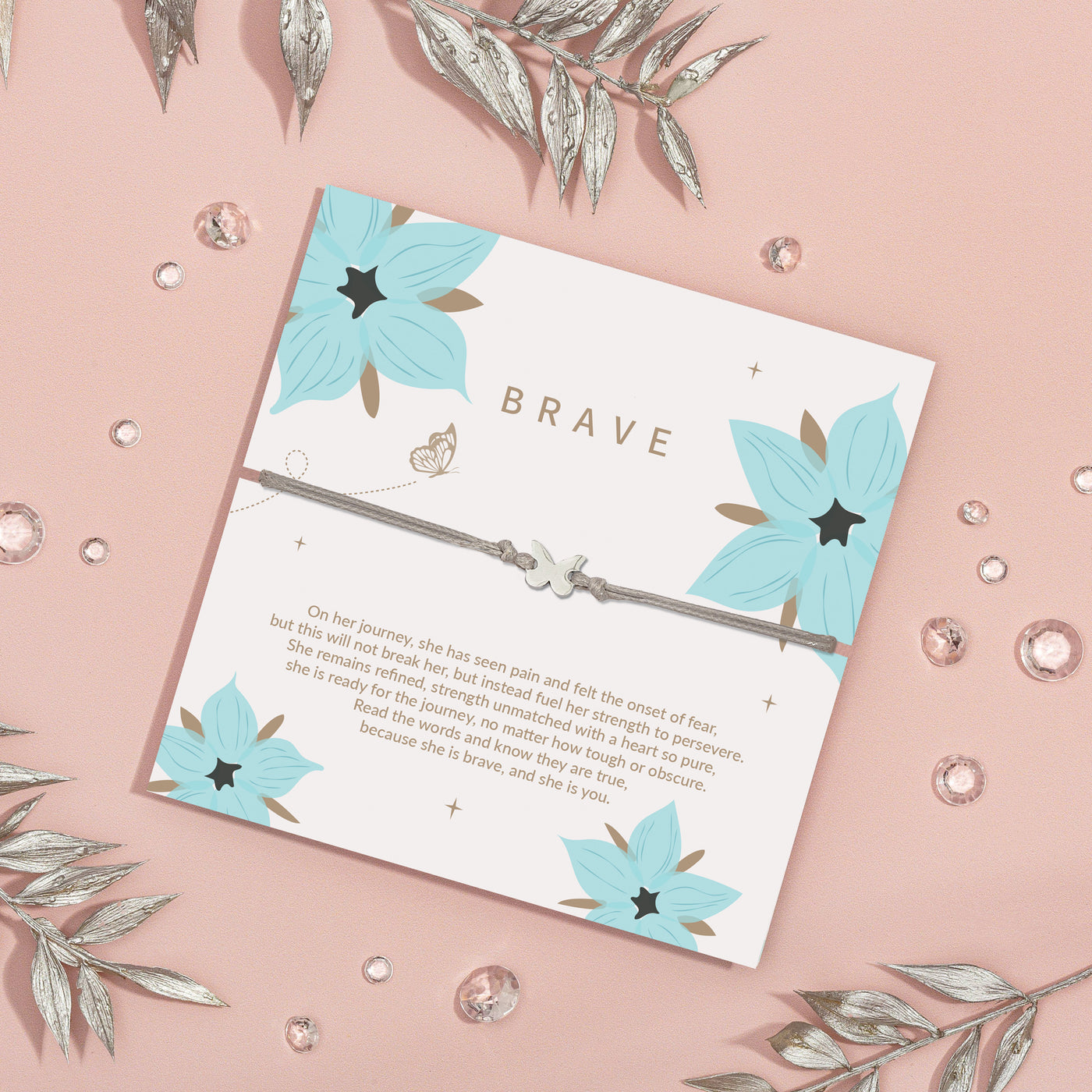 Silver bracelet with a butterfly charm presented on a white 'BRAVE' card decorated with teal flowers and a touching message about strength and perseverance.
