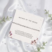Silver bracelet on a card for 'Mother of the Bride' with decorative elements on a white fabric background. An elegant bracelet for the Mother of the Bride.