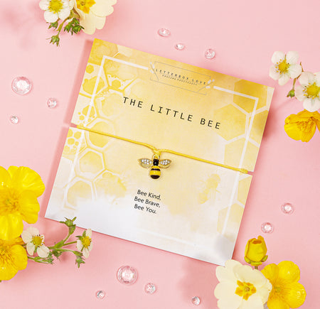 Yellow-themed bracelet card featuring a charming bee charm with sparkling wings, set on a yellow string. The card has a honeycomb pattern background and displays the title 'The Little Bee' along with the inspiring message 'Bee Kind, Bee Brave, Bee You.' Surrounded by yellow and white flowers, this bracelet is a delightful and uplifting gift that encourages kindness and bravery