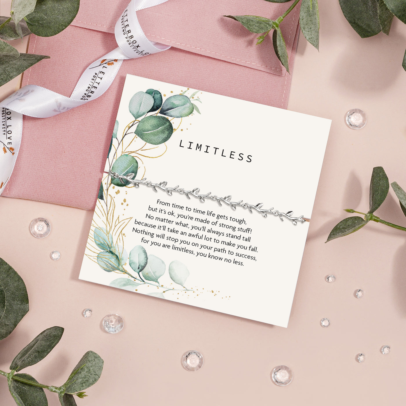 A 'LIMITLESS' encouragement card by Letterbox Love, set on a pastel pink background. The card features elegant botanical illustrations with silver eucalyptus leaves and gold accents. Encouraging gift for a friend.