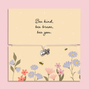 Adjustable cord bracelet with silver bee charm and heart charm displayed on a floral “Bee Kind Bee Brave Bee You” message card, inspirational encouragement gift bracelet for friend or daughter.
