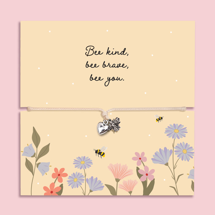 Adjustable cord bracelet with silver bee charm and heart charm displayed on a floral “Bee Kind Bee Brave Bee You” message card, inspirational encouragement gift bracelet for friend or daughter.