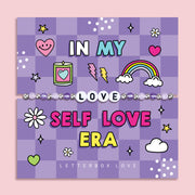 Purple chequered poem card with the bold text saying "In My Self Love Era", with a beaded bracelet spelling the word "Love". An ideal gift for a best friend or a self-love jewellery gift