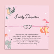 Pink adjustable string bracelet with two silver interlocking heart charms, displayed on a card that reads "Lovely Daughter" with an illustrated fox, raccoon, and poem.