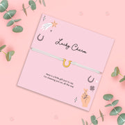 Pink card with 'Lucky Charm' text and illustrations on a pink background with green leaves.
