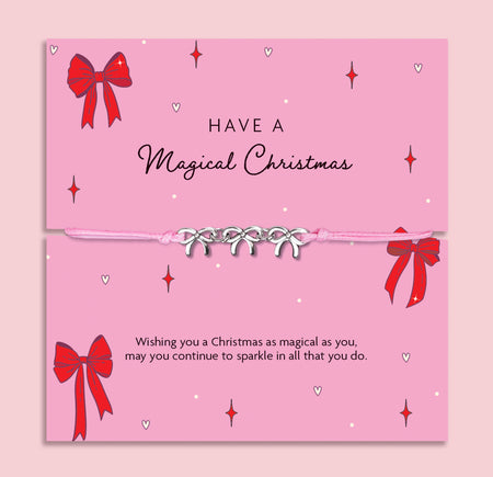 Pink Christmas card with red bows and decorative text on a pink background with a friendship bracelet with bow charms. A meaningful gift under £10 for Christmas.