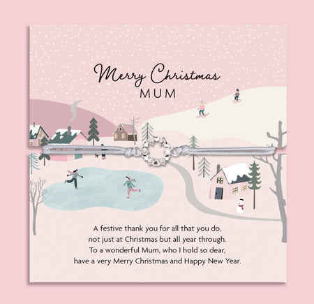 Merry Christmas Mum bracelet featuring a silver wreath charm on an adjustable cord, presented on a festive pink card with snowy village scene, skiers, and ice skaters. Includes a soft white pouch for gifting and safekeeping. A thoughtful Christmas jewellery gift for mum, perfect as a stocking filler, Christmas morning surprise, or sentimental keepsake. A meaningful bracelet designed to show love and appreciation this holiday season.