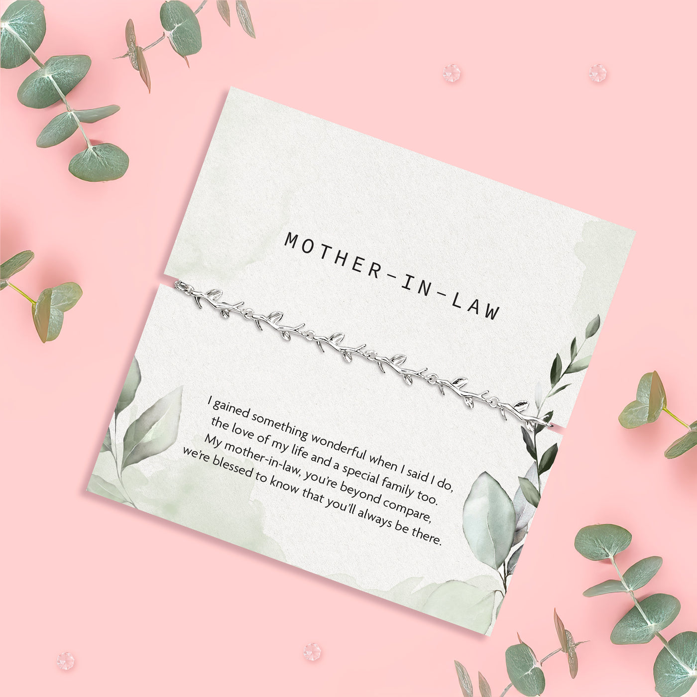 a pale pink background with eucalyptus leaves and mother-in-law poem card with silver-plated vine bracelet