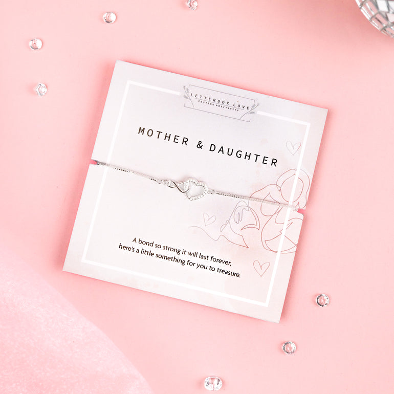 A pink background with a white poem card with a cute mother and daughter embracing. The bracelet is an elegant silver-plated infinity and heart bracelet, creating the perfect Mother's Day gift