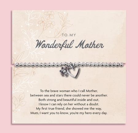 A silver beaded bracelet with a heart and flower charm displayed on a card reading 