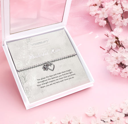 Silver beaded bracelet with heart and flower charms, displayed in a white gift box alongside a card titled 