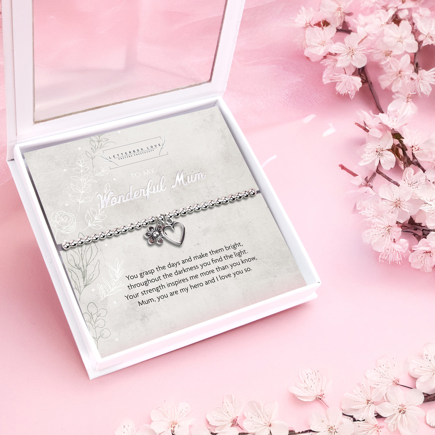 Silver beaded bracelet with heart and flower charms, displayed in a white gift box alongside a card titled 