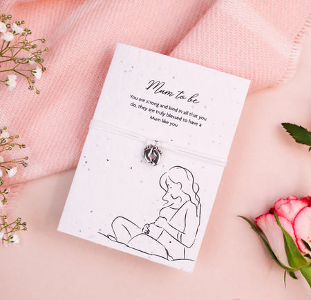 Letterbox Love Mum to Be bracelet with silver baby feet charm, set on a card with a 'Mum to be' message and illustration of a pregnant woman. Thoughtful gift for expectant mothers, featuring eco-friendly seed paper design.