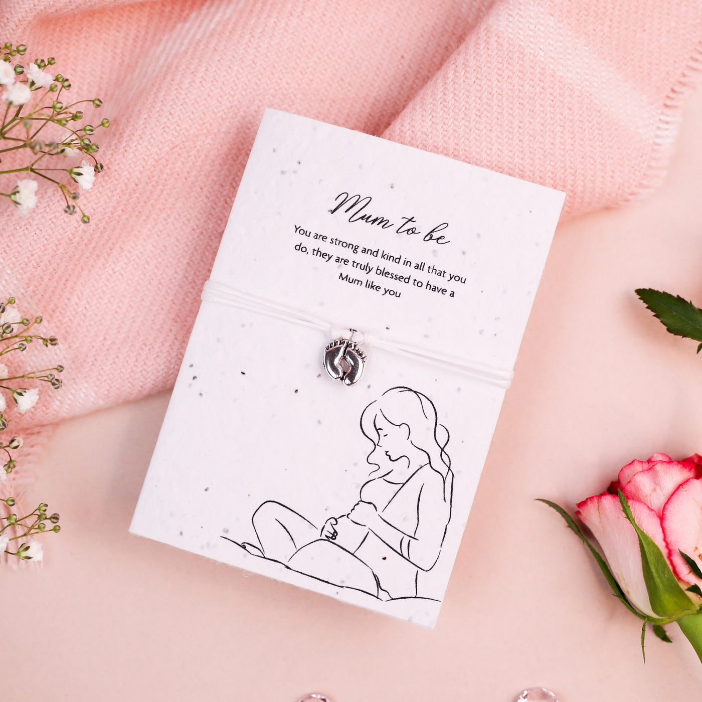 Letterbox Love Mum to Be bracelet with silver baby feet charm, set on a card with a 'Mum to be' message and illustration of a pregnant woman. Thoughtful gift for expectant mothers, featuring eco-friendly seed paper design.