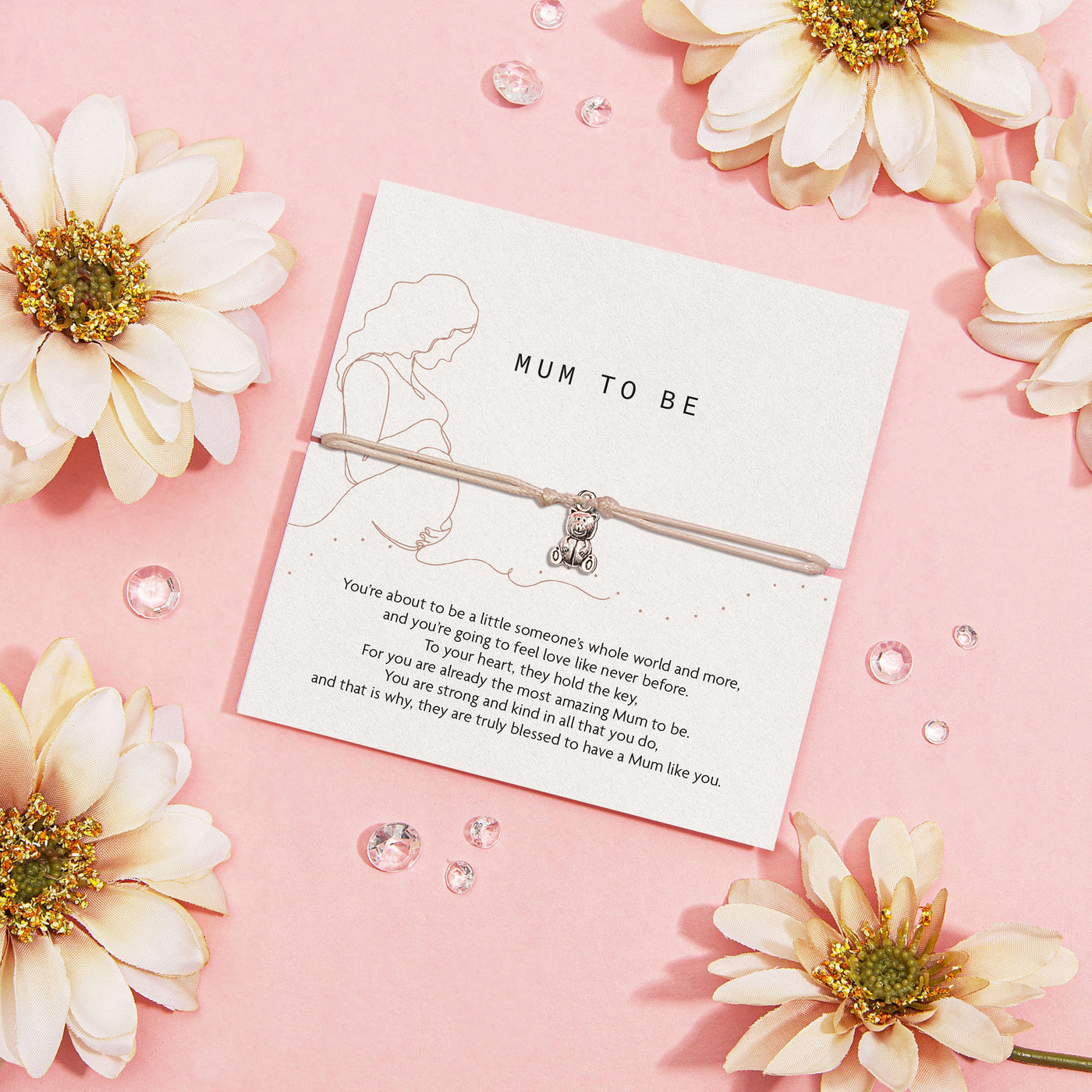 Bracelet with 'Mum to Be' charm on a card surrounded by flowers on a pink background